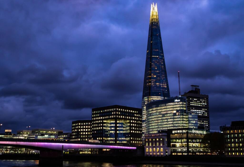 The Shard skyscraper illuminated at night, standing tall over the London skyline with city lights glowing below